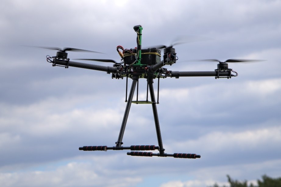 Large FPV quadcopter in flight against an overcast sky
